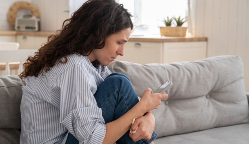 A woman sitting on a couch looking at her phone.