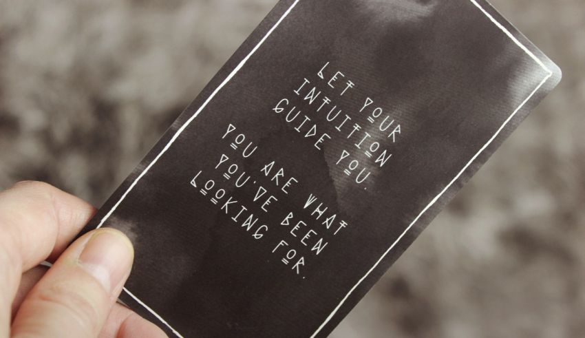 A hand holding a black paper with white text.