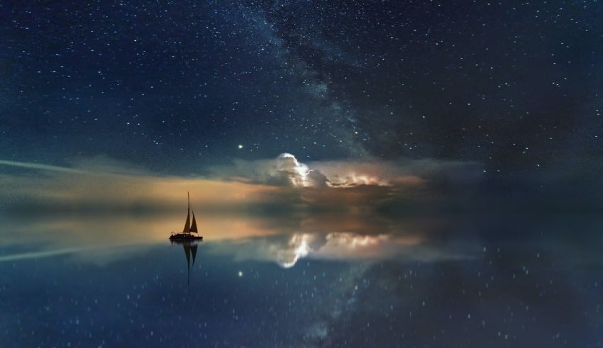 A sailboat is floating in the water under a starry sky.