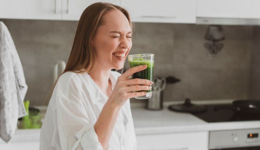 A woman drinking green juice in the kitchen.