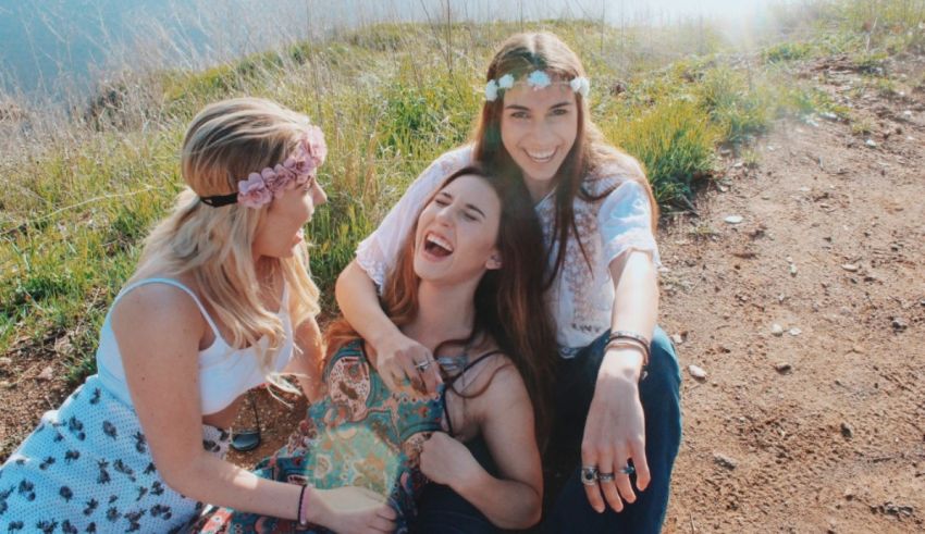 Three young women sitting on a hill and laughing.