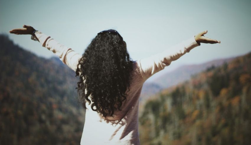 A woman standing on a mountain with her arms outstretched.