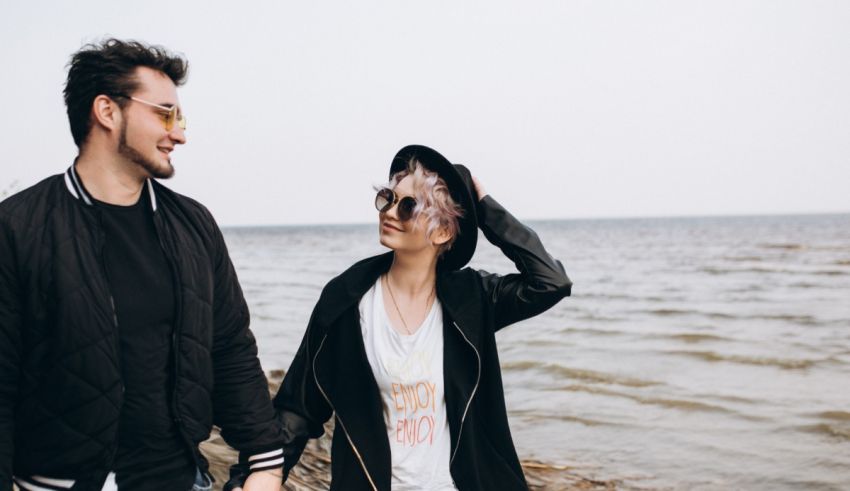 A young man and woman are holding hands on the beach.