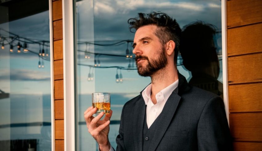 A man in a suit holding a glass of whiskey.