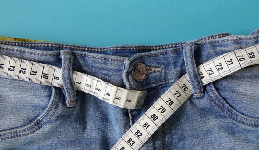 A woman is measuring her jeans with a measuring tape.