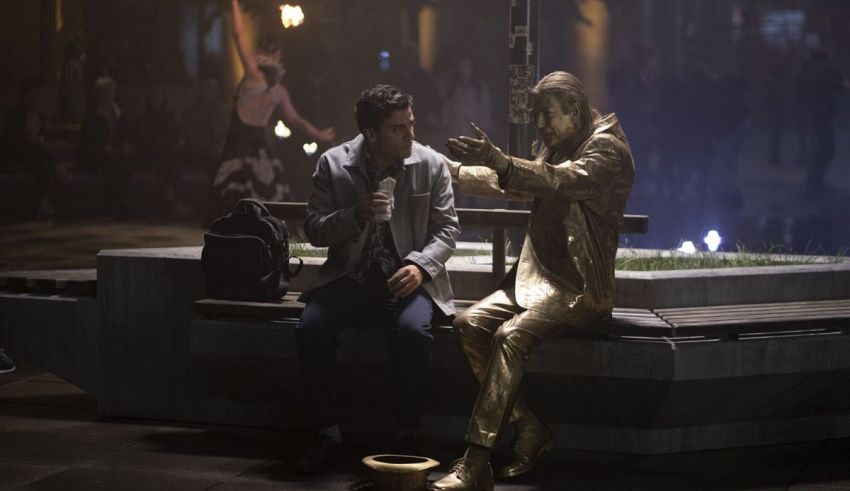 A man sitting on a bench next to a golden statue.