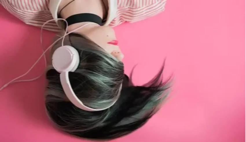 A mannequin wearing headphones on a pink background.