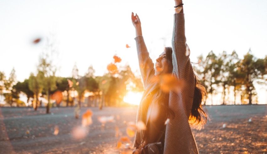 A woman with her arms up in the air at sunset.