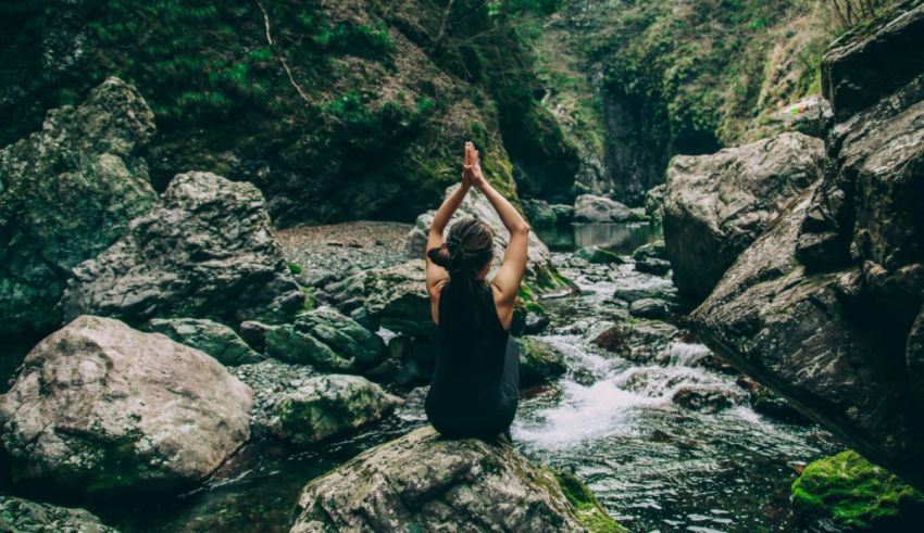 A woman practicing yoga on rocks in a mountain stream.