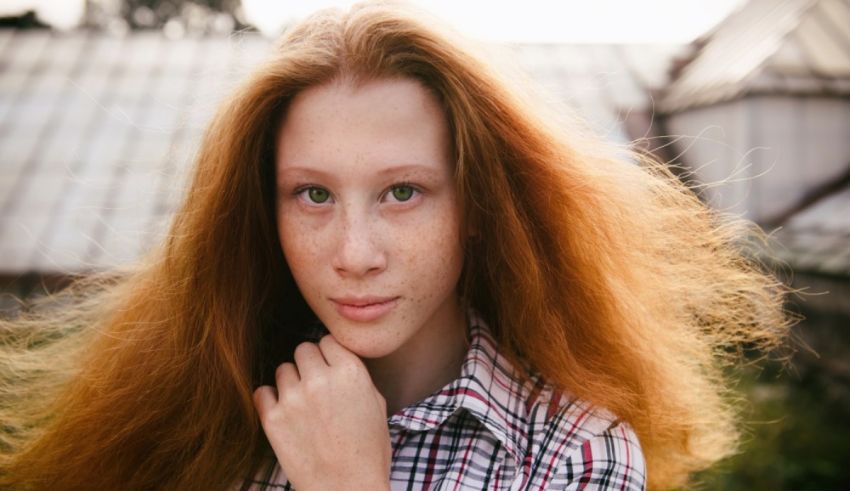 A young girl with red hair is posing for a photo.