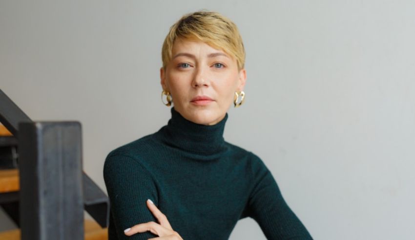 A woman in a green turtle neck sweater sitting on a staircase.