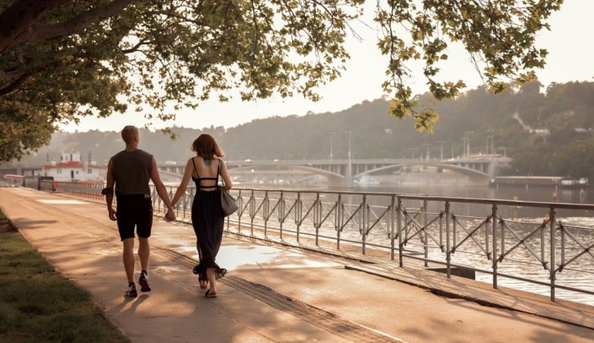 A man and woman are walking down a sidewalk near a river.