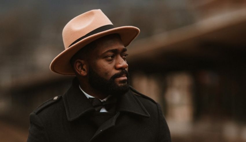 A man in a hat is standing on a train platform.