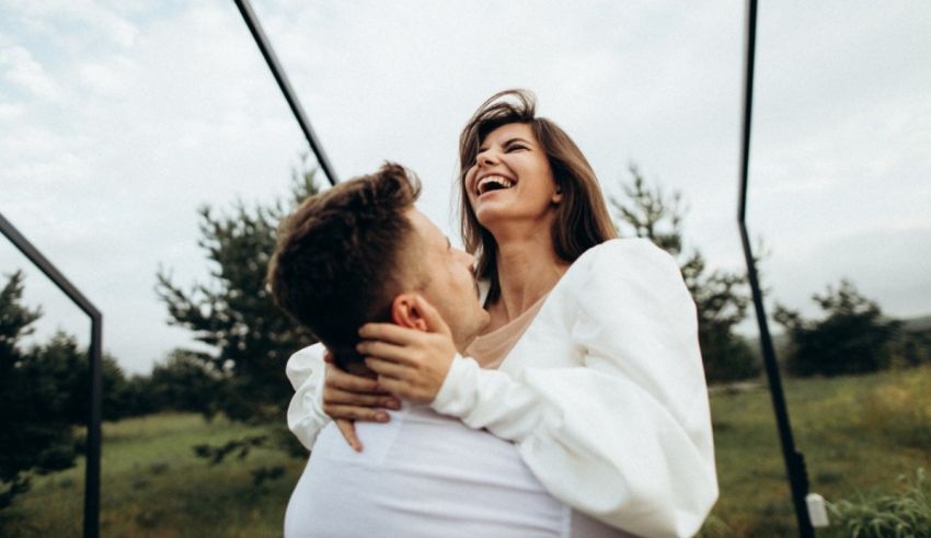 A man and woman hugging in the middle of a field.