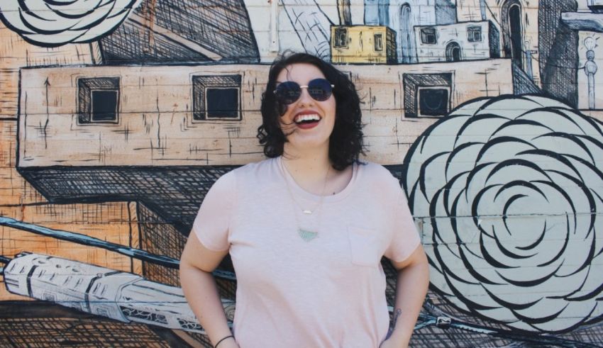 A woman in sunglasses standing in front of a mural.