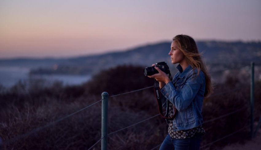 A woman holding a camera at sunset.