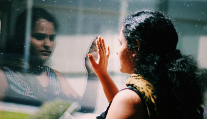 A woman looking at her reflection in a window.