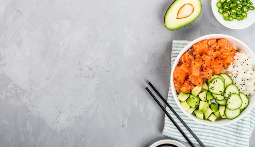 A bowl of salmon, cucumber and avocado on a gray background.
