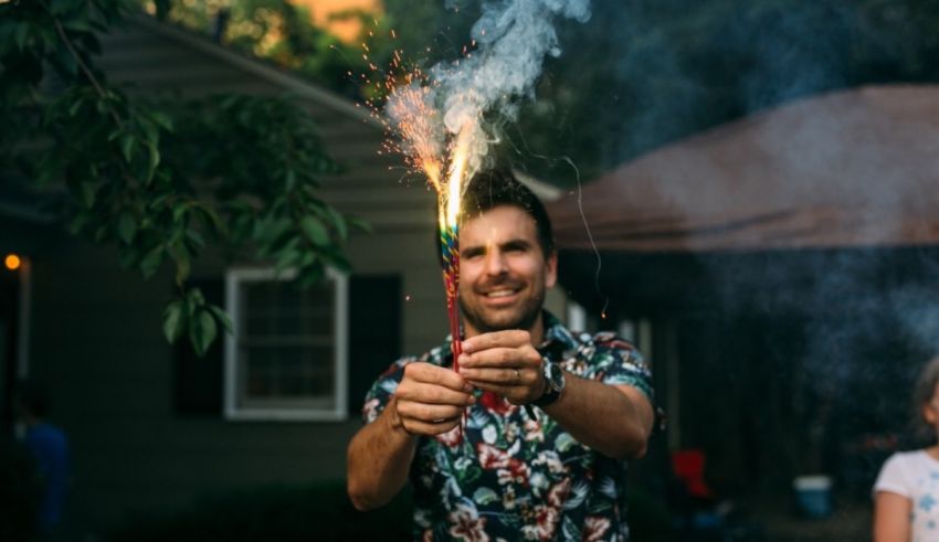 A man holding a sparkler at a backyard party.