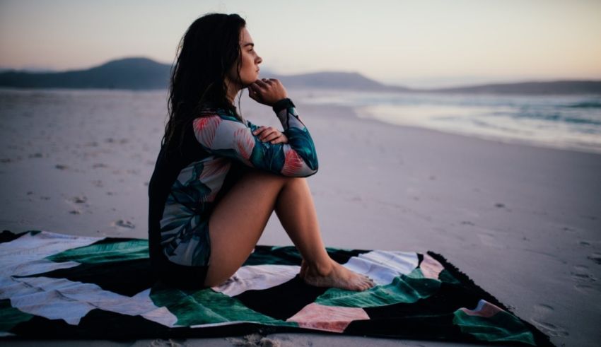 A woman sitting on a towel on the beach.