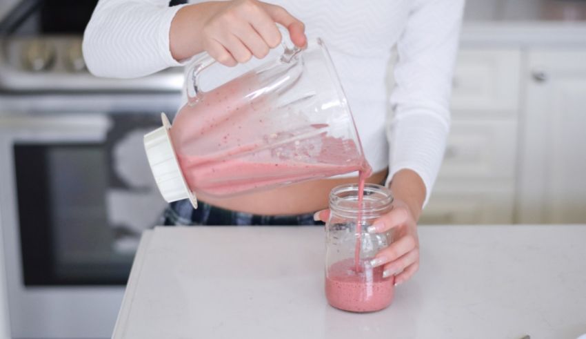 A woman pouring a smoothie into a glass jar.