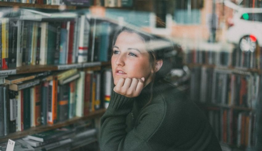 A woman looking out of a window in a bookstore.