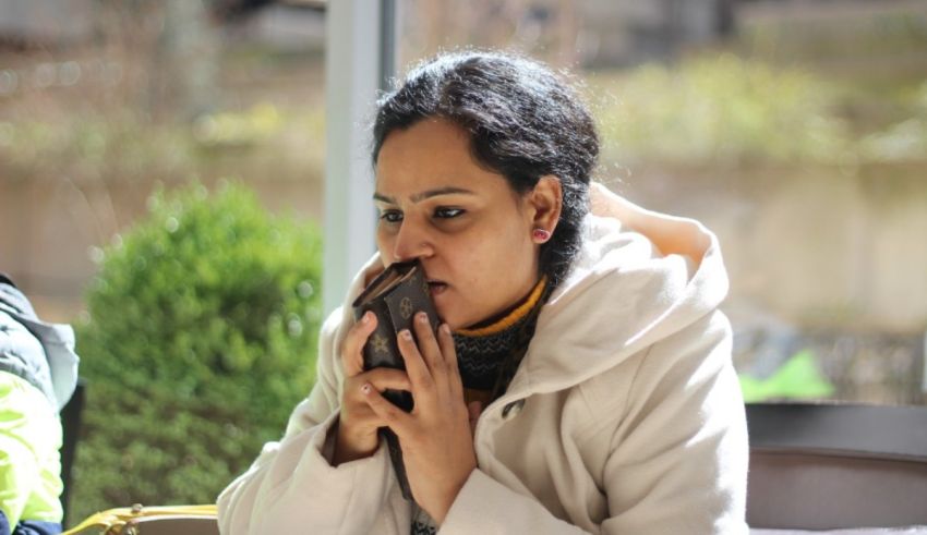 A woman sitting at a table eating a piece of chocolate.