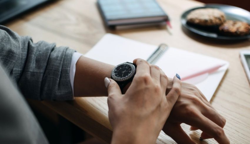 A woman's wrist with a watch on it at a desk.