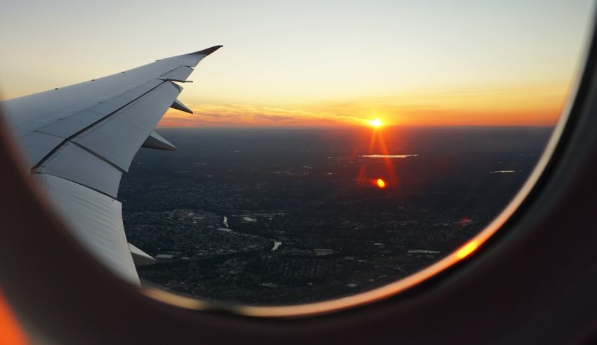 An airplane wing with the sun setting behind it.