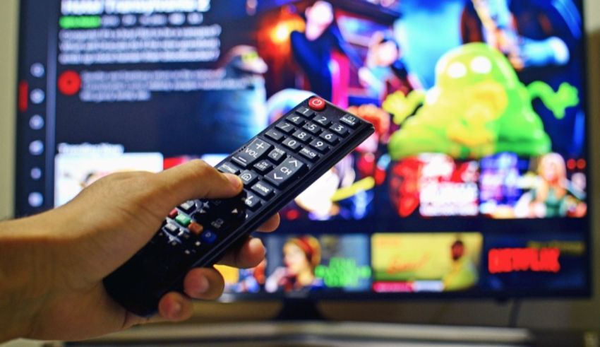 A person holding a remote control in front of a television.