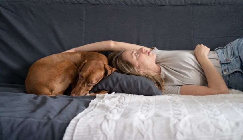 A woman laying on a bed with her dog.