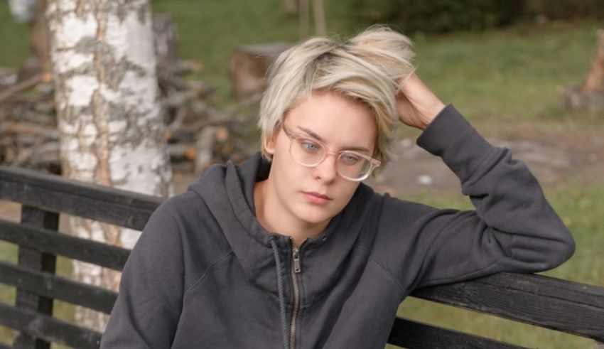 A young woman with glasses sitting on a bench.