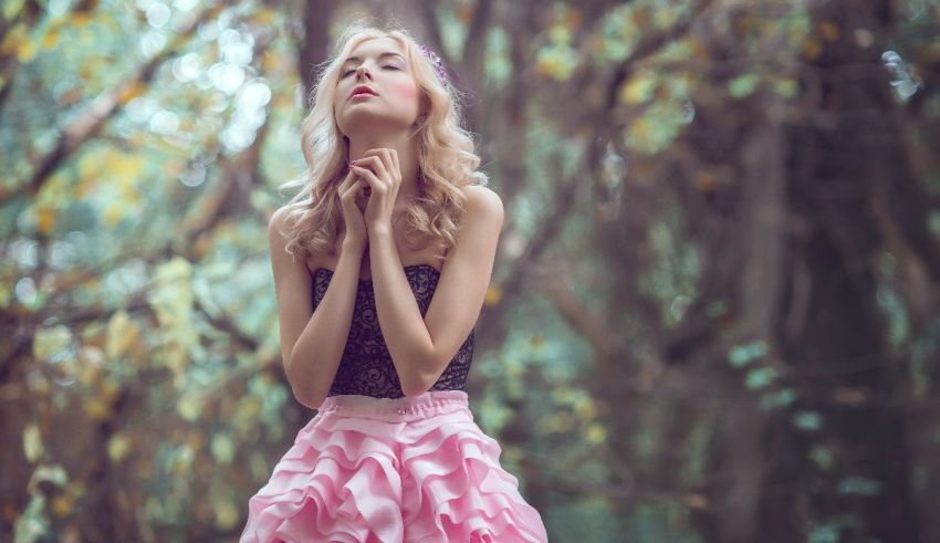 A beautiful woman in a pink dress posing in the woods.