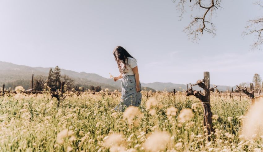 A woman walking through a field of flowers.