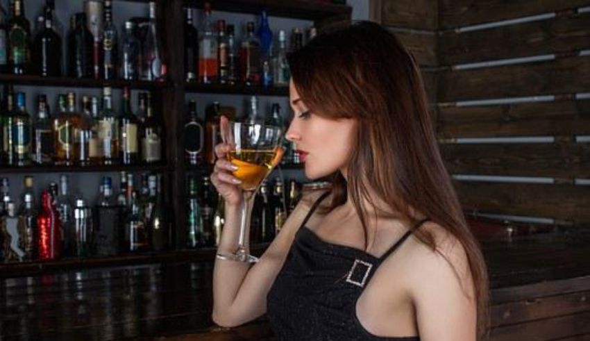 A woman drinking a glass of wine in a bar.