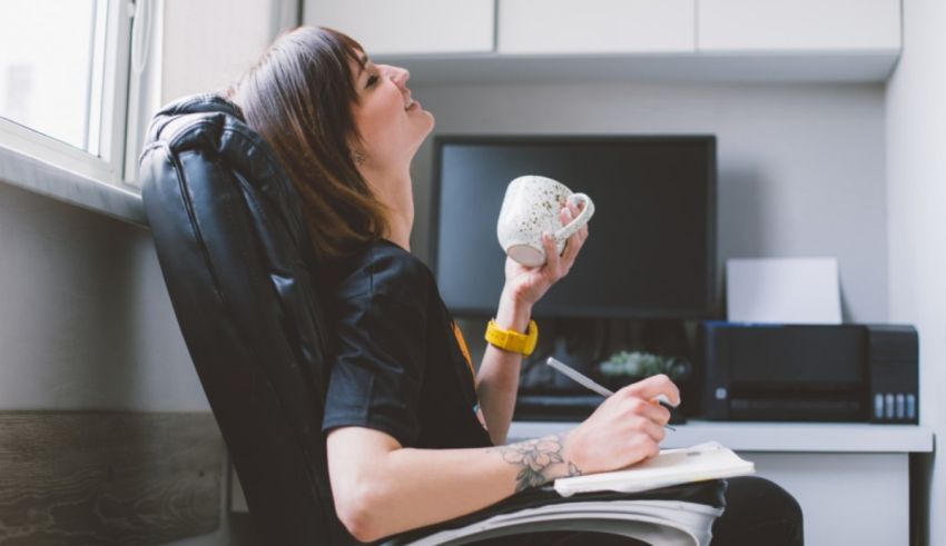 A woman sitting in an office chair with a cup of coffee.