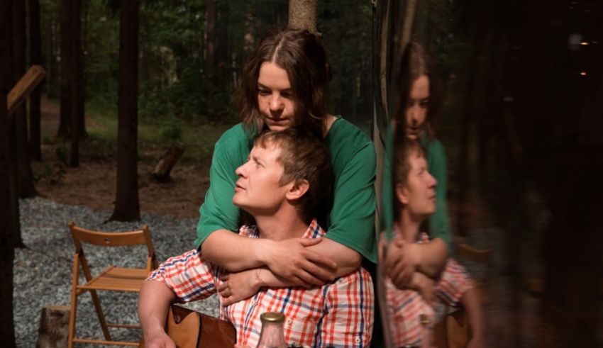 A man and woman hugging in the woods.