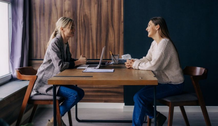 Two women talking at a table in an office.