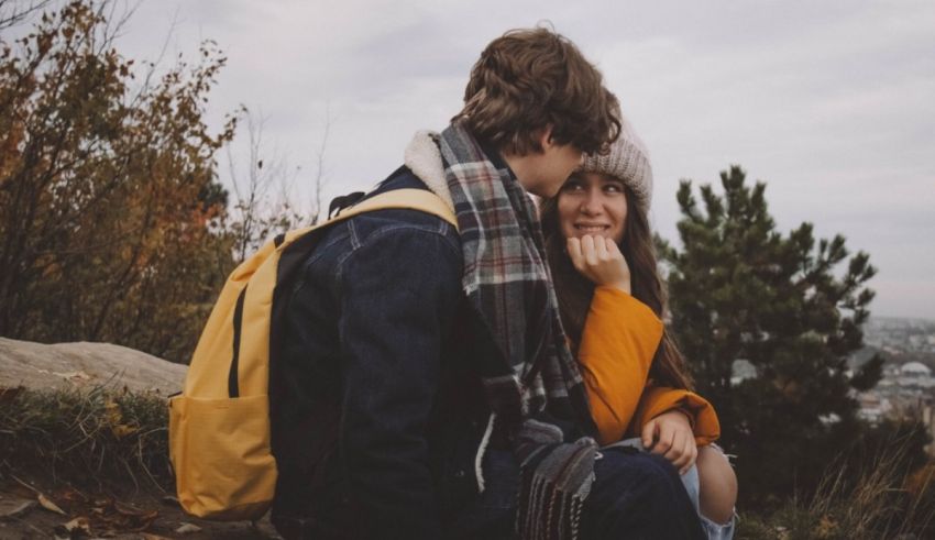 A couple sitting on a hill and hugging each other.