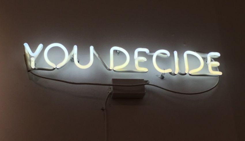 A neon sign that says you decide on a wall.