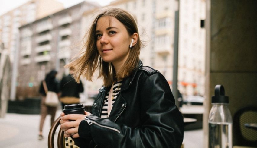 A woman in a leather jacket is holding a cup of coffee.