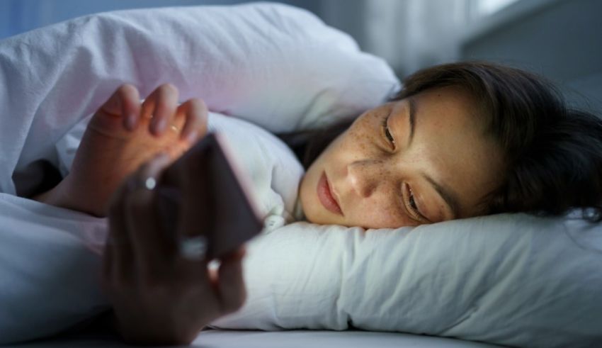 A woman is laying in bed with her phone in her hand.