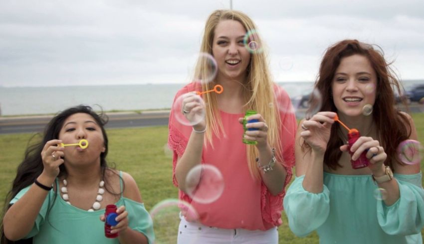 Three girls blowing soap bubbles on the beach.