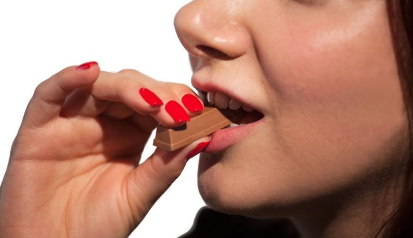 A woman is biting into a chocolate bar.