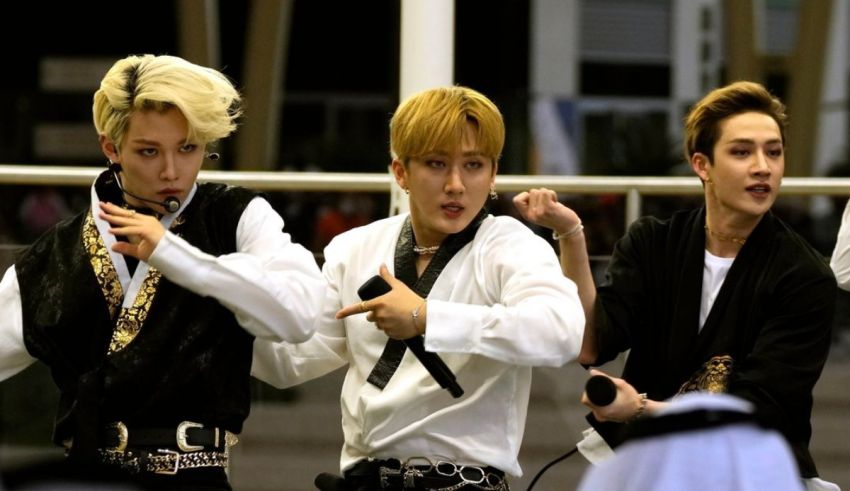 Four korean boys are performing in front of a crowd.