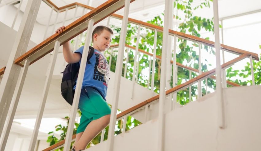 A young boy is climbing the stairs in a school building.