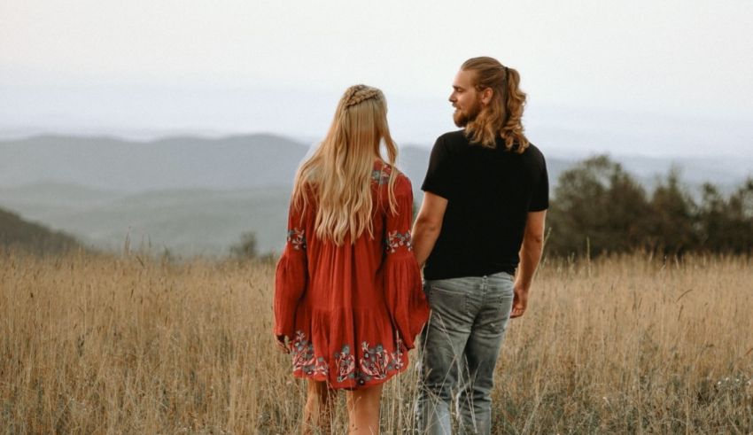A couple standing in a field with mountains in the background.