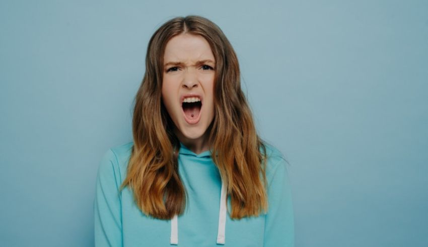 A young woman screaming against a blue background.