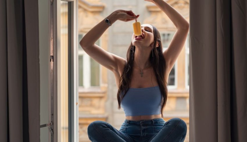 A woman drinking orange juice from a window sill.