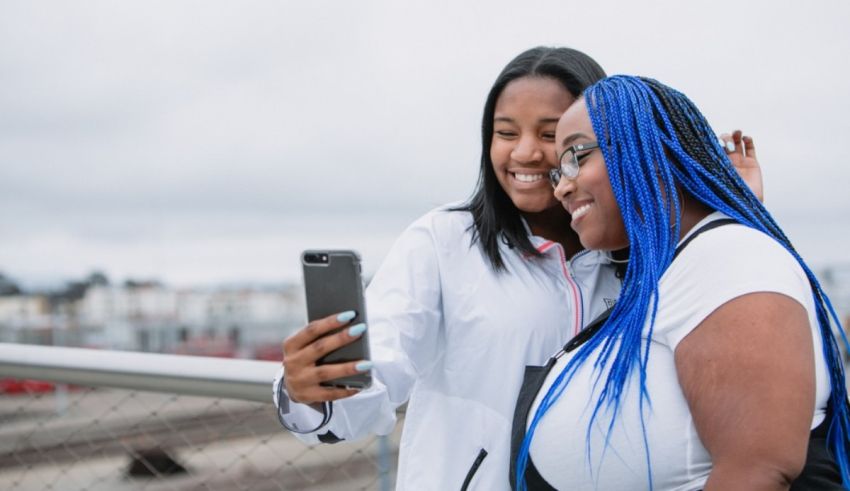 Two black women taking a selfie on a bridge.